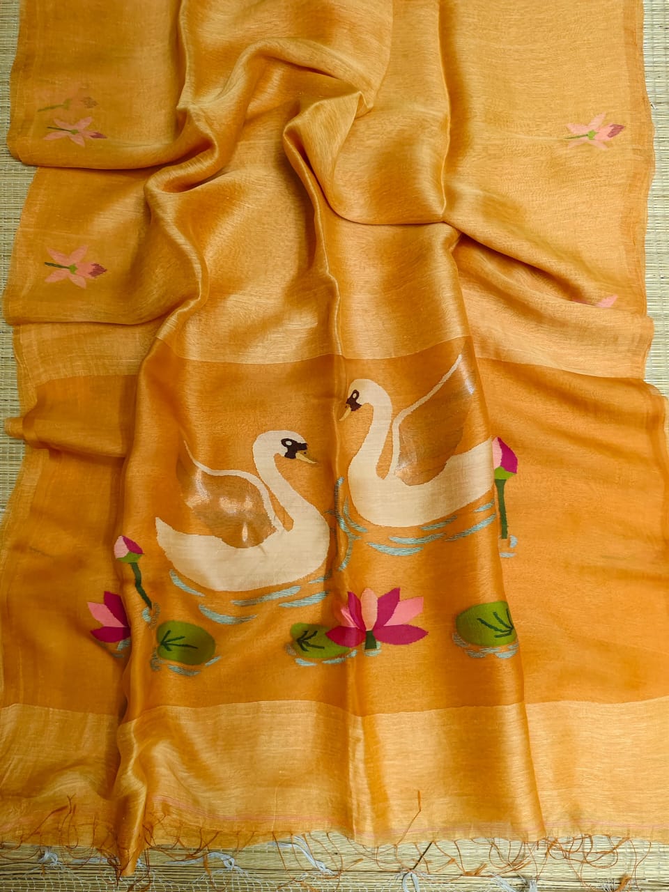 Yellow fabric with embroidered swan designs on a woven surface