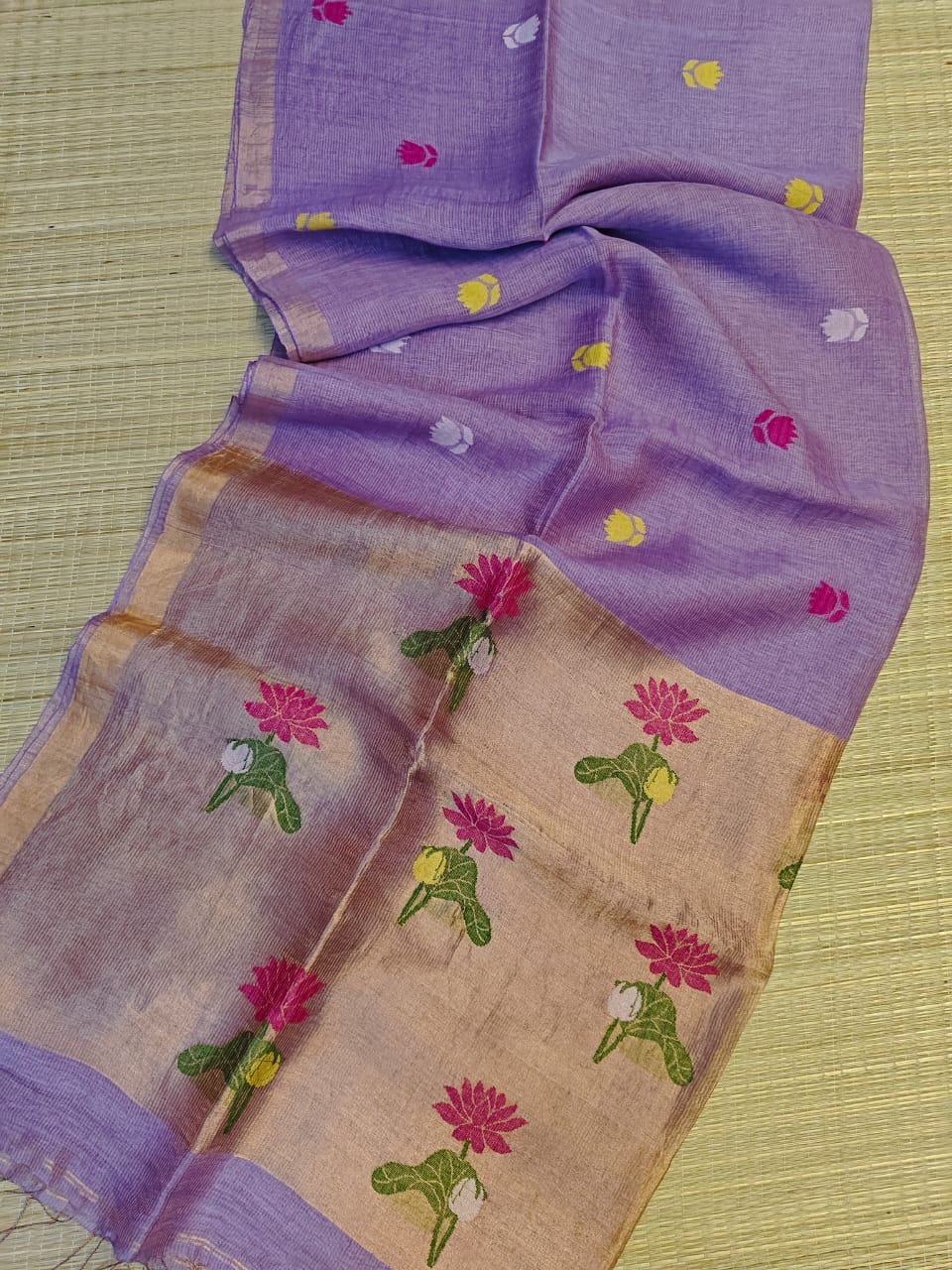 Purple and beige saree with floral patterns on a green background