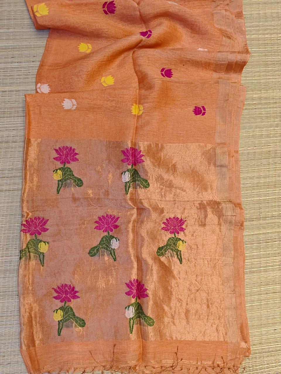 Orange saree with floral patterns on a textured surface