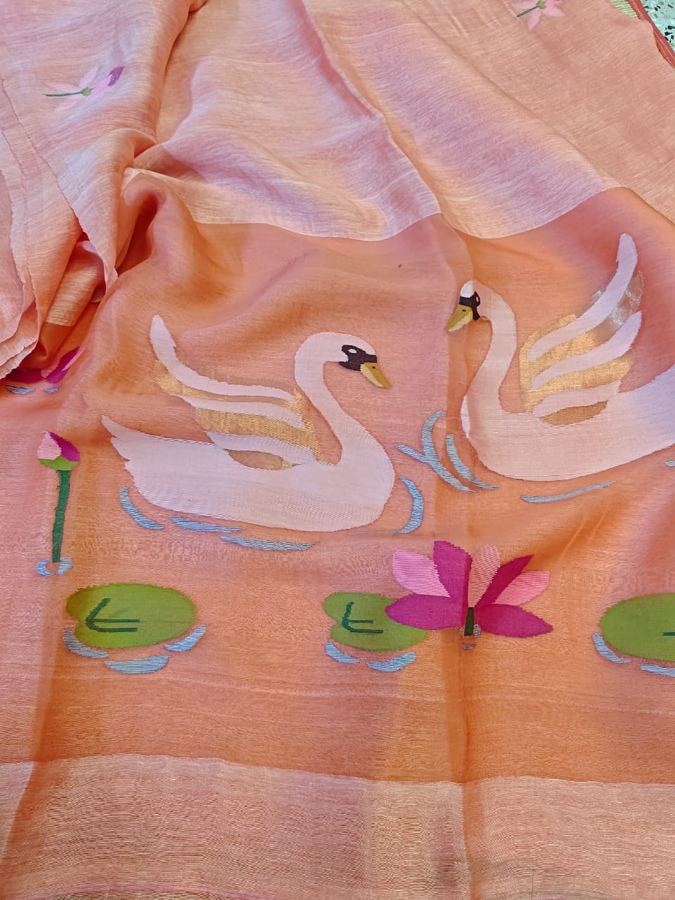 Embroidered fabric with swan design on a peach background