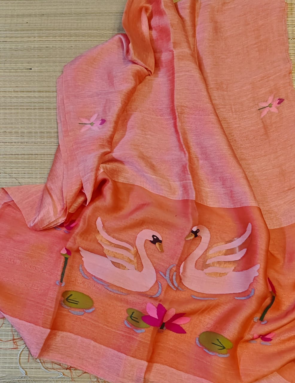 Light pink fabric with swan and lily pad designs on a woven background