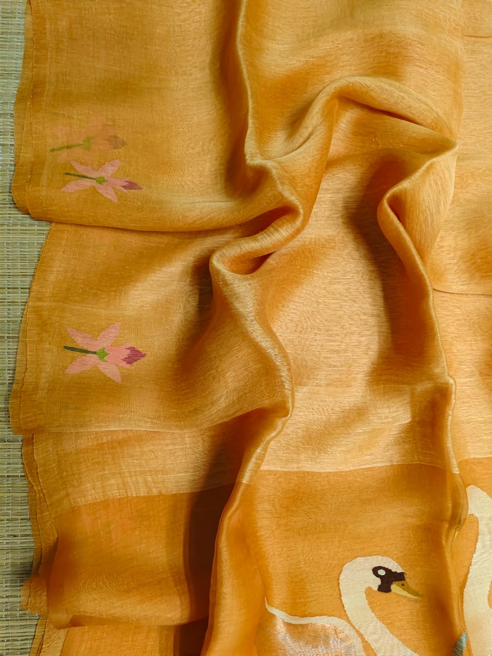 Close-up of yellow fabric with floral embroidery on a textured surface