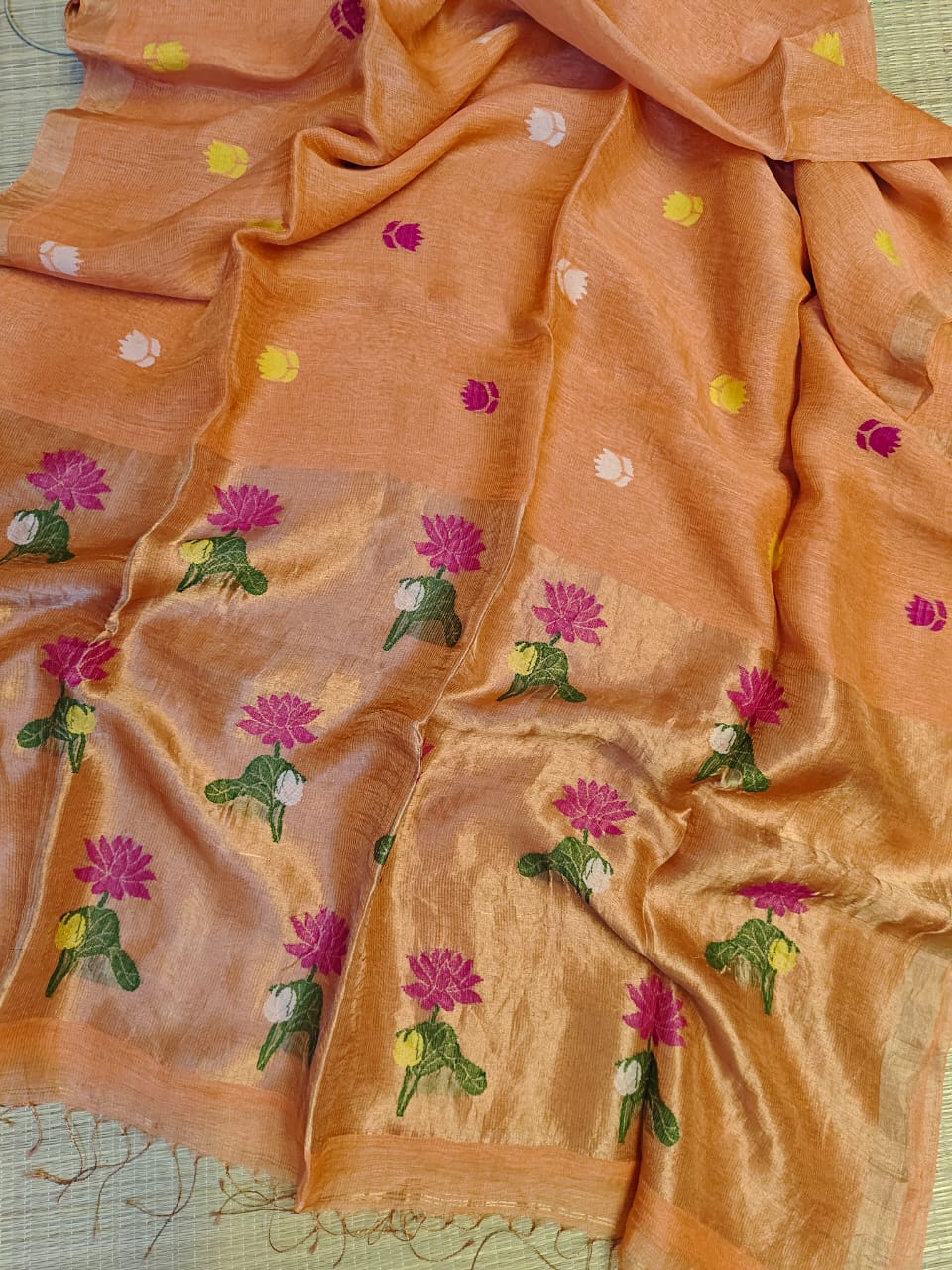 Orange saree with floral embroidery on a textured surface