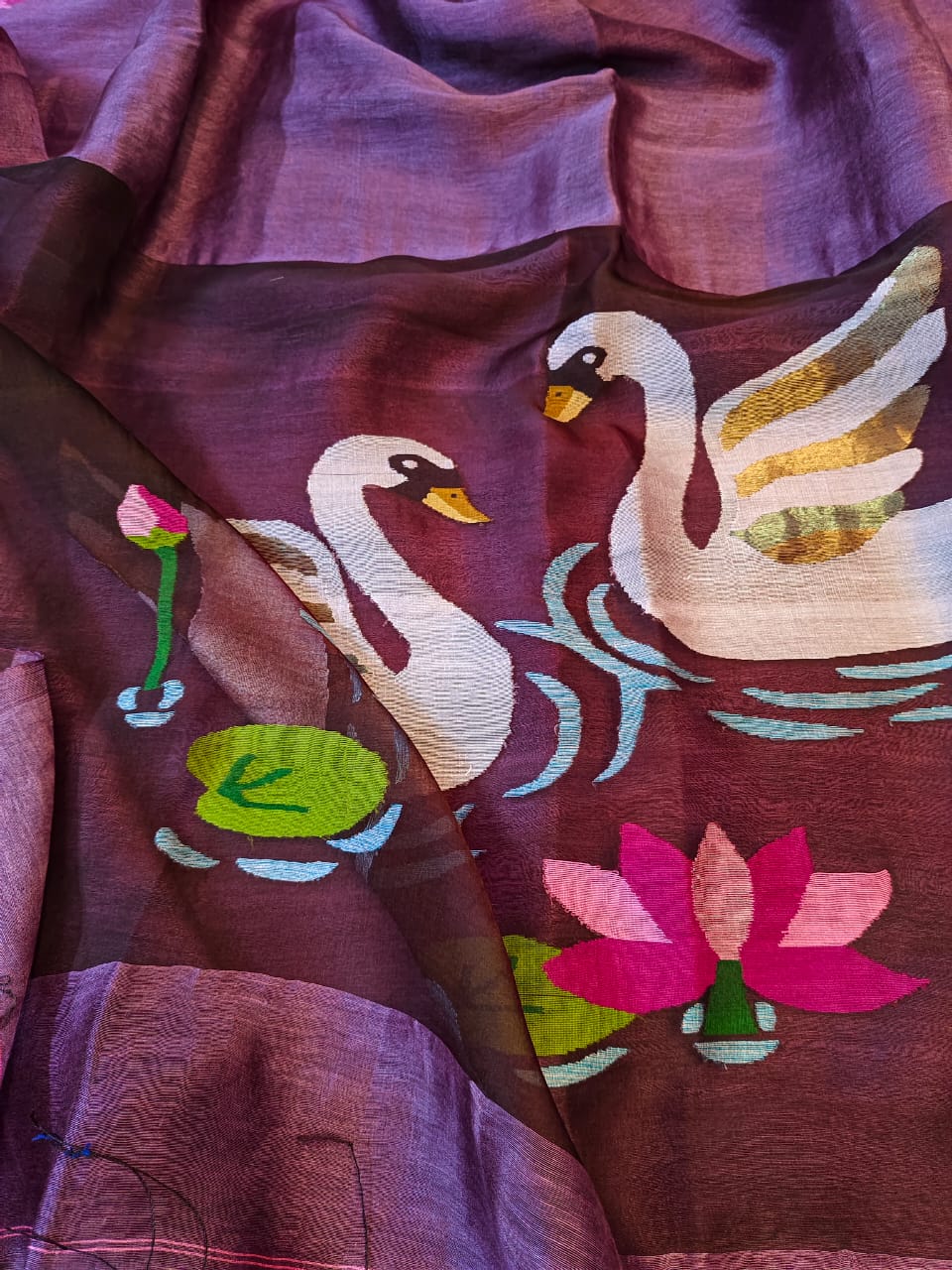 Embroidered fabric with swans and lotus flowers on a maroon background