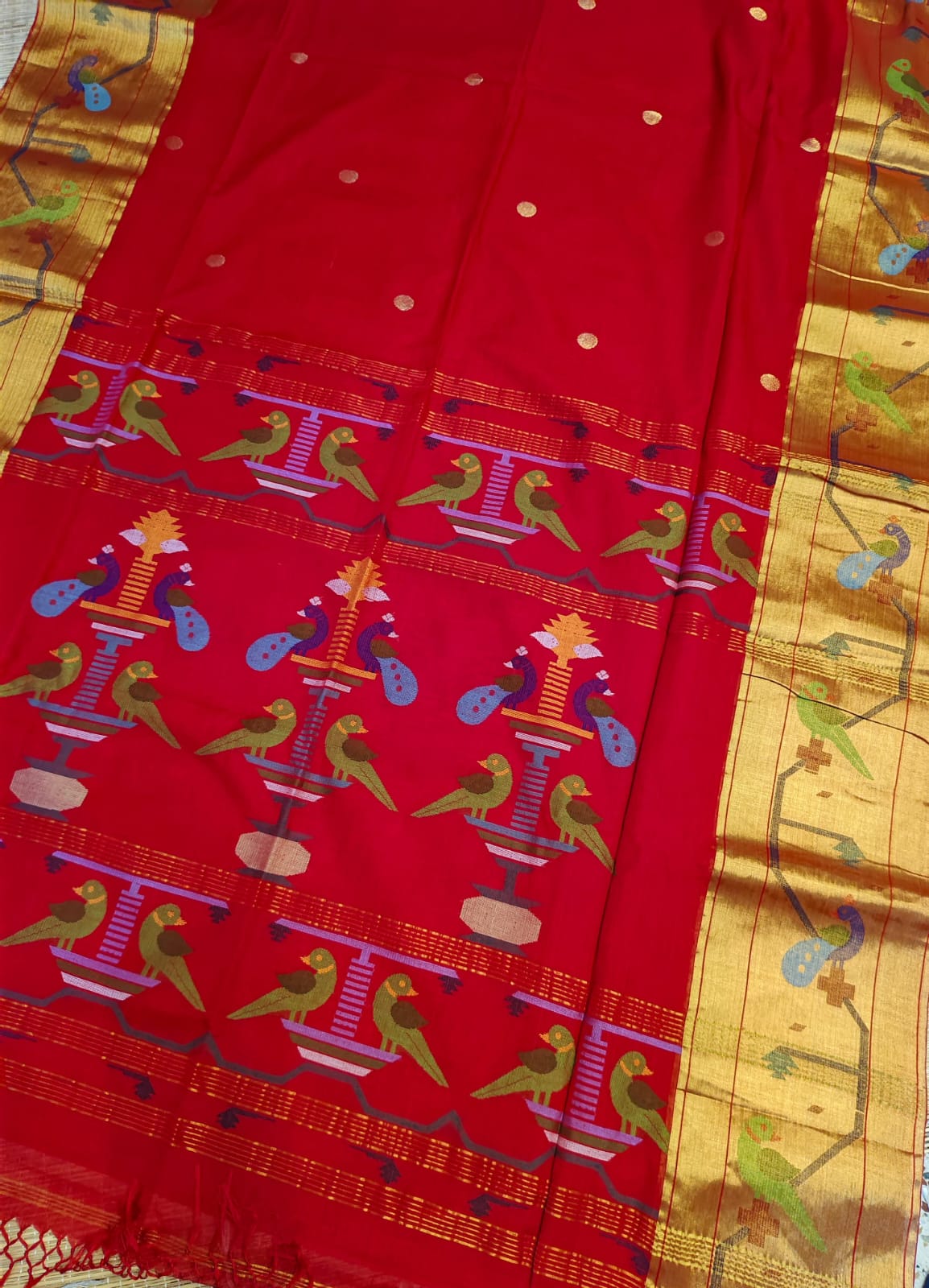 Red fabric with colorful bird patterns on a gold background