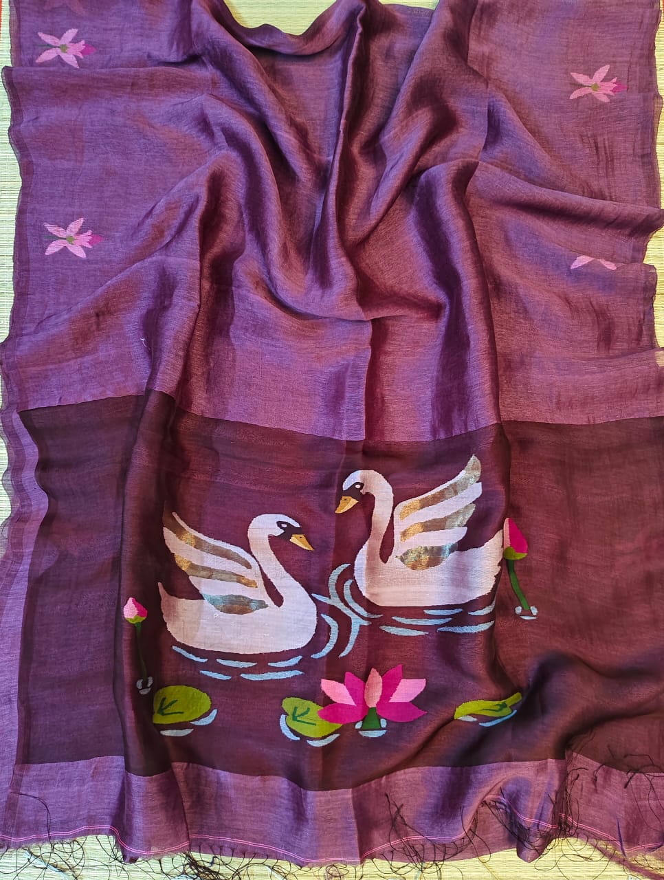 Purple fabric with embroidered swans and lilies on a green background