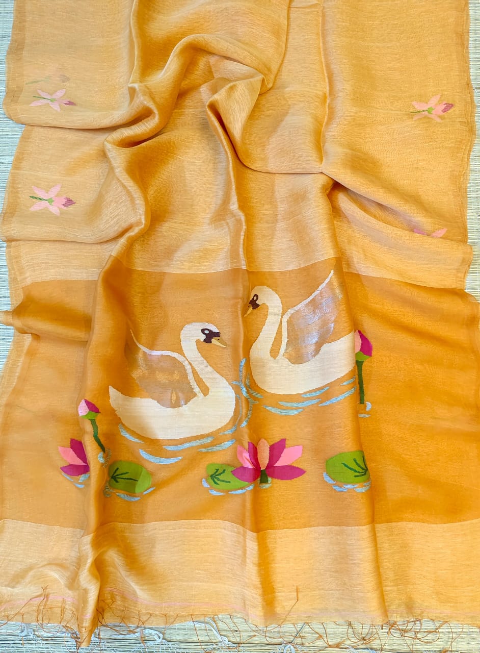 Yellow fabric with embroidered swans and lilies on a blue surface